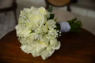Illustration: A bouquet of white roses resting on a round wooden surface in soft light.