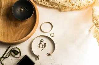 Illustration: A top-down view of delicate gold jewellery displayed on bowls and flat surfaces.