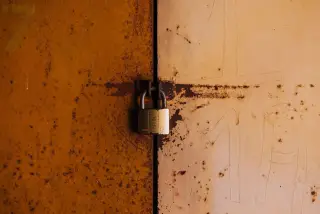 Illustration: A padlock securing a rusty, weathered metal door.