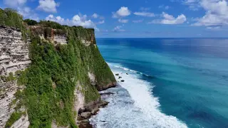 Illustration: Steep coastal cliffs with green vegetation meet a turquoise ocean with white waves.