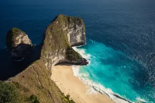 Illustration: High-angle view of Kelingking Beach with dramatic cliffs, sandy cove, and turquoise waters.