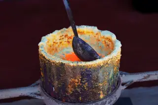 Illustration: Close-up of molten metal glowing inside a smelting crucible with a metal ladle.