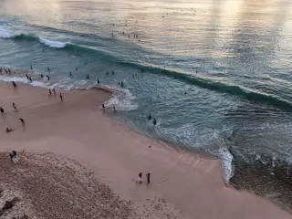 Illustration: Aerial view of people on a sandy beach and in the ocean waves.