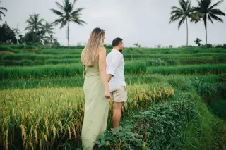 Illustration: A couple holds hands while walking along a path between terraced rice fields.