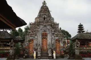Illustration: An ornate stone temple gate with golden carved doors in Bali.