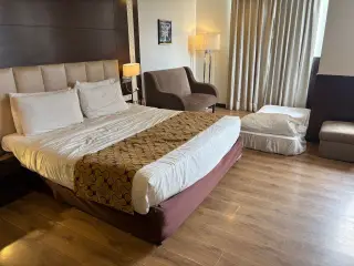 Illustration: A furnished hotel room with a double bed, armchair, and an extra floor mattress.