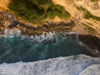 Illustration: An aerial view of ocean waves breaking against a rocky coastline and cliffs.