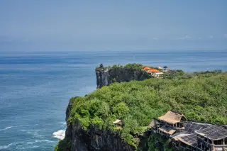 Illustration: A cliff covered in lush greenery with coastal buildings overlooking the blue sea.