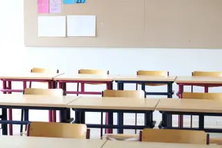 Illustration: Empty classroom with neatly arranged wooden desks and chairs facing a board.