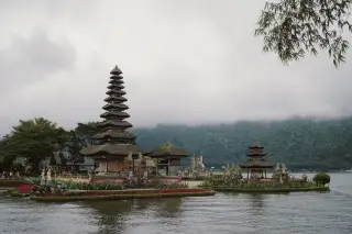 Illustration: A multi-tiered Balinese temple on the edge of a lake against misty mountains.