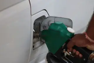 Illustration: A hand holding a green fuel nozzle while refuelling a white car.