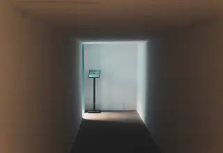 Illustration: A quiet, empty corridor with a small signpost standing in the light at the end.