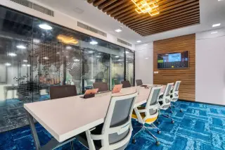Illustration: Modern boardroom with a conference table, chairs, glass wall with world map, and screen display.