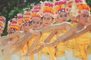Illustration: A group of Balinese dancers perform in ornate gold costumes and floral headdresses.