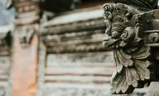 Illustration: A close-up of a detailed stone carving on an ornate Balinese temple wall.