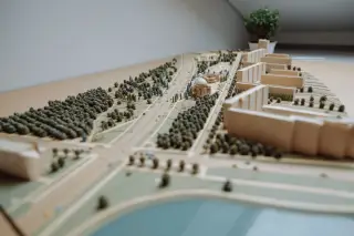 Illustration: An architectural scale model of an urban development with buildings, streets, and miniature trees.