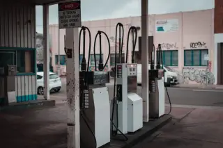 Illustration: Several fuel dispenser pumps standing in an empty petrol station.
