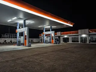 Illustration: A brightly lit Pertamina gas station forecourt stands quiet at night.