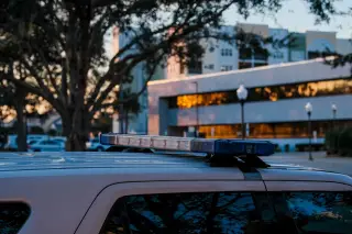 Illustration: A close-up of a vehicle light bar on top of a car parked on an urban street at dusk.