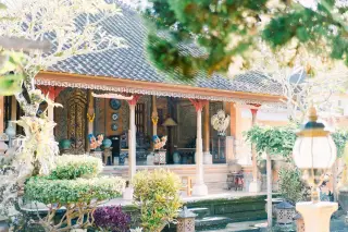 Illustration: A traditional Balinese pavilion featuring intricate carved pillars and statues in a lush garden.