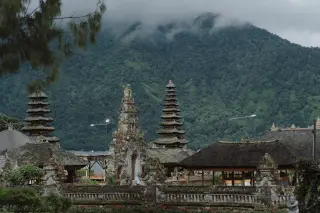 Illustration: A Balinese temple complex with tiered shrines set against a misty, forested mountain.