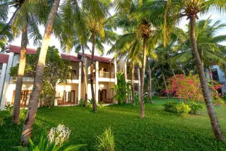Illustration: A two-story tropical resort building nestled behind tall palm trees and a lush green lawn.
