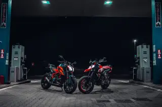 Illustration: Two modern motorcycles parked between fuel pumps at a petrol station at night.