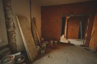 Illustration: Interior of a building under renovation with exposed brick walls, boards, and paint buckets.