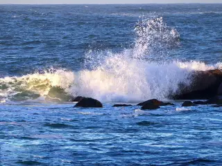 Illustration: Ocean waves crash against coastal rocks, creating white sea spray.