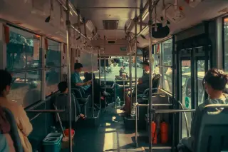 Illustration: Interior of a city bus showing passengers seated along the aisle during daytime.