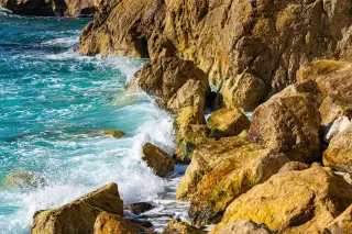 Illustration: Turquoise ocean waves crashing against rugged, sunlit coastal rocks.