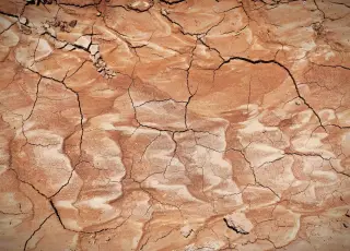 Illustration: Close-up view of dry, cracked reddish-brown soil.