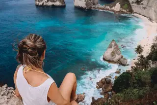 Illustration: A woman sits on a cliff overlooking turquoise ocean waters and a tropical beach.