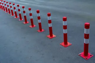 Illustration: A row of red and white traffic bollards fixed along an asphalt road surface.