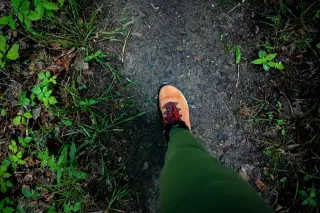 Illustration: Top-down view of a person's foot in a hiking boot walking on a dirt trail.
