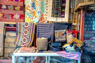Illustration: Traditional woven textiles and handcrafted items displayed in an artisan shop.