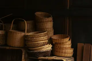 Illustration: Stacks of woven bamboo baskets arranged neatly against a dark wooden background.