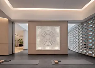 Illustration: A modern, empty yoga studio interior with mats and an illuminated wall art piece.