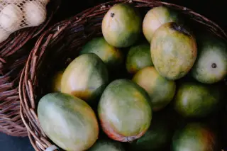 Illustration: Close-up view of fresh mangoes arranged in a rustic woven basket.