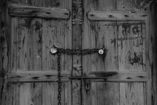 Illustration: A rustic wooden door locked with a chain and two padlocks in black and white.