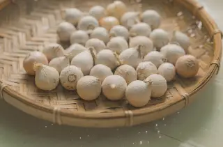 Illustration: A woven bamboo tray filled with small single-clove garlic bulbs.