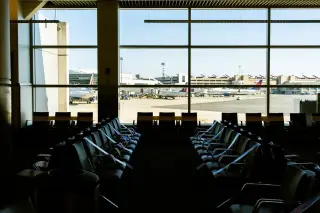 Illustration: Empty airport terminal seats facing large windows overlooking the tarmac and airplanes.