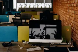 Illustration: An empty modern office desk with a computer monitor, keyboard, and headphones.